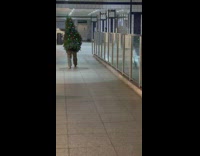 Guy wearing christmas tree walks around station 