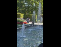 Girl stands water fountain ledge dress garden 