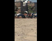 Guy lays on beach while birds go sit on him