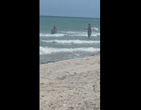 Lady in Bikini Stands with Hand on Knee in Water 