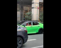 Man in Joker costume drives green car