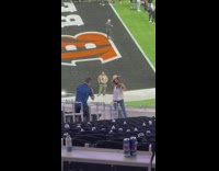 Woman with white hat poses on the bleachers of the super bowl