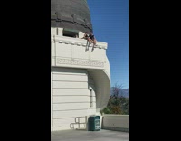 Girls sits edge wall Griffith Observatory takes picture