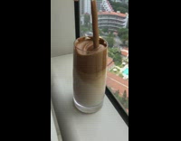 Girl stirs dalgona coffee in tall glass cup