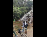 Man flexes his body muscle in front of the waterfalls