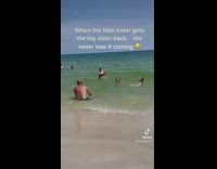 Little sister dunks head in ocean water