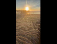 Huge sand art maze pattern on beach