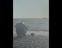 Woman takes picture of the Santa hat at the beach