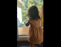Little girl waves at the window inside and wait her sister