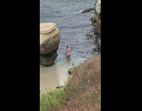 Guy black polo shirt beside rock beach