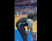 Girl in nets jersey dribbling on sidelines at game
