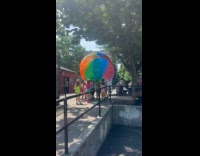 Kids help carry massive beach ball