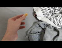 dog eats snack from under grey striped bed sheets