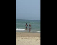 Woman in jean shorts and hat stands on the beach