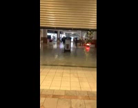 Group of people running to beat metal gate at mall closing