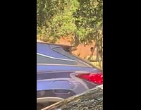 Woman in black sports bra spins for a selfie on the basketball court