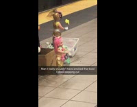 Man plays the xylophone with dancing dolls around him at the subway station