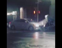 Wind blows white canopies around silver car