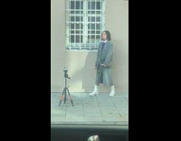 Woman in grey coat poses at the sidewalk