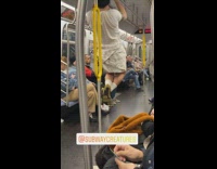 Guy white shirt hands from handrail on ceiling on subway train