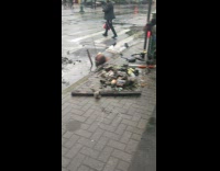 Guy lays in dirty water next to sidewalk 