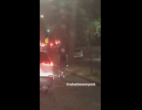 Guy rides a one wheel hoverboard down the street with flashing backpack lights