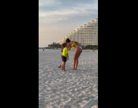 Woman setup phone beside kid at beach