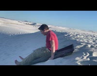 Kid goes down sand hill on sled