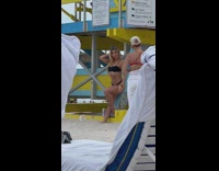 Woman in black bikini leans on the lifeguard house