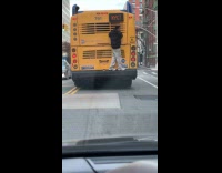 Man hitching behind bus 