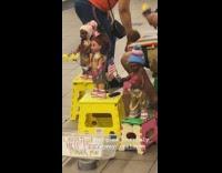 Man shakes maracas with dancing dolls around him at subway station