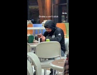 uy in black hoodie on phone eating in cafeteria looks like drake 