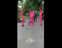Four people in pink bodysuits dance to Hotline bling in the park