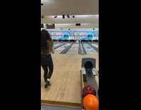 Girl gets bowling strike with blue ball