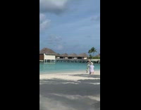 Woman in cyan dress poses at the beach shore