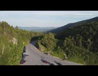 Drone flies over mountain trees cars pond 
