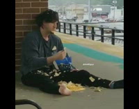 Guy sits on the ground  and eats Tostito chips off the floor at subway station