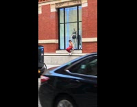 Girl with red work out outfit hanging on building