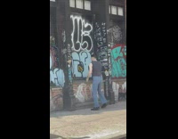 Guy dances in front of graffiti wall for video 