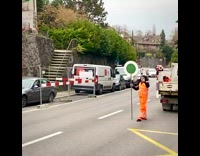 Guy rides skateboard past traffic construction worker 