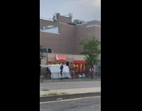 Guy ride tall unicycle in front of stores 