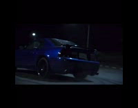 Blue car does donuts around asphalt 