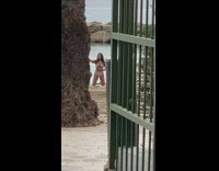Woman in bikini kneels and selfie video at the beach