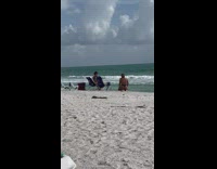 Woman in black bikini kneels with a peace sign