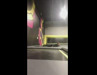 Guy backflips and spins on indoor trampoline park and lands on the ground