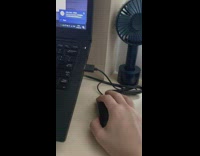 Cat grabs mouse from behind laptop