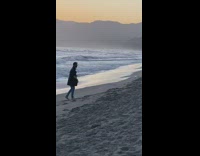 Guy move black coat beach sunset waves