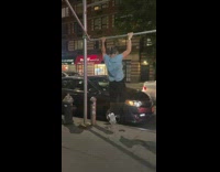 Guy in blue does pull-ups on sidewalk 