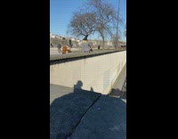 Girl jean jacket sitting on edge of wall over train tracks 