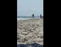 Shirtless guy black shorts beach red flag 